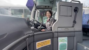 送迎バスの運転席に座る30代の女性バス運転手