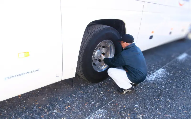 タイヤの点検をしているベテランのバス運転士